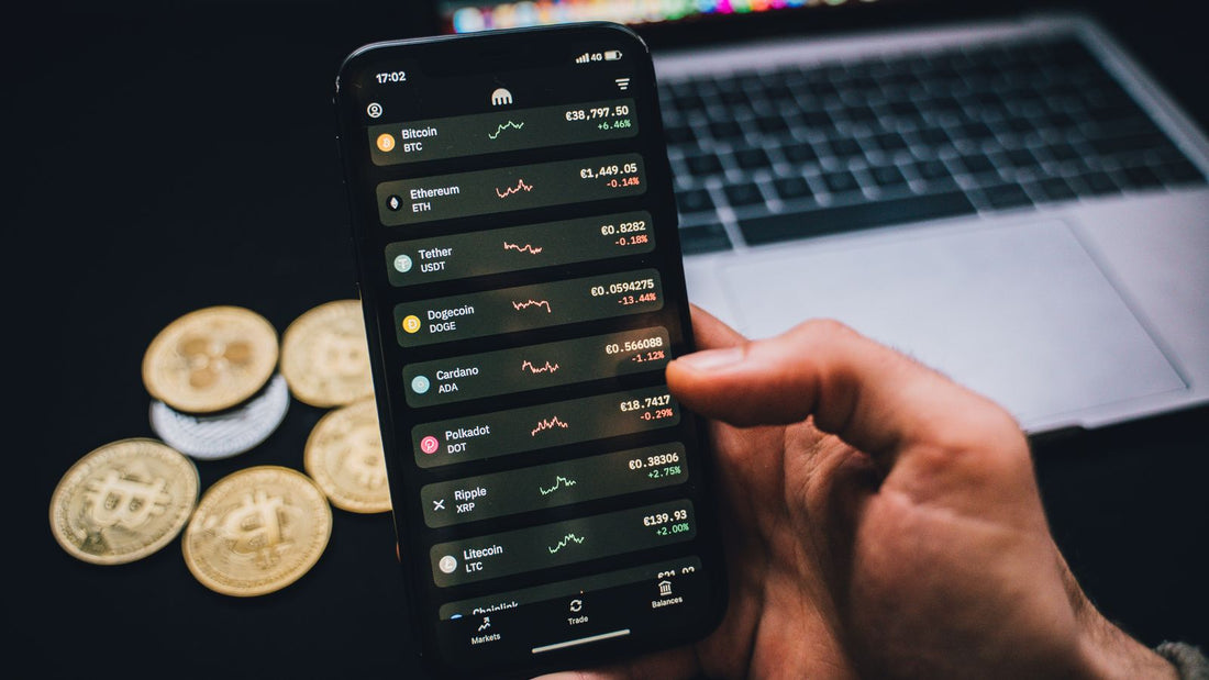 Persona che consulta grafici di mercato su smartphone, con Bitcoin su scrivania