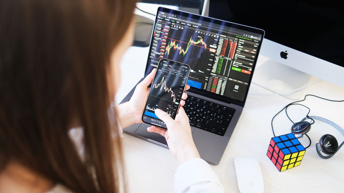 Investitrice al computer e allo smartphone per l'acquisto e l'analisi delle criptovalute