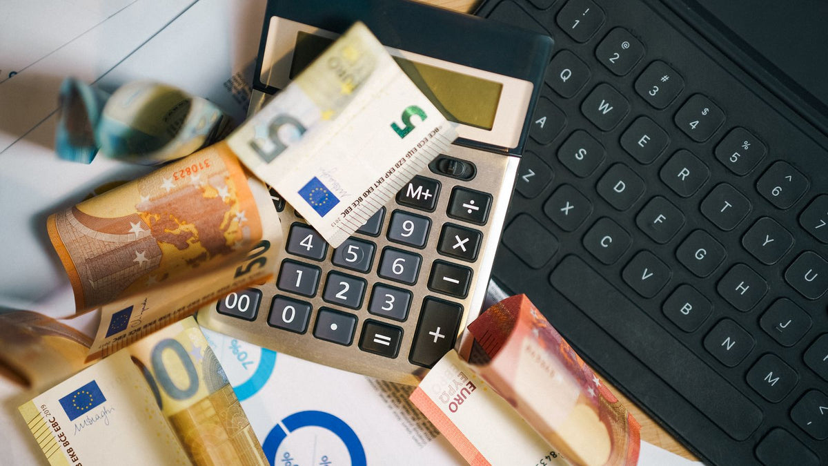 Calcolatrice accanto a documenti finanziari, costi e commissioni degli investimenti