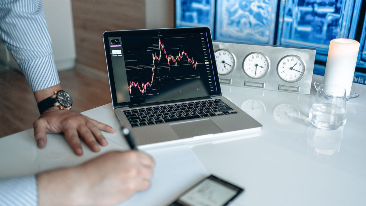 Analista finanziario al computer con appunti, calendario e orologio