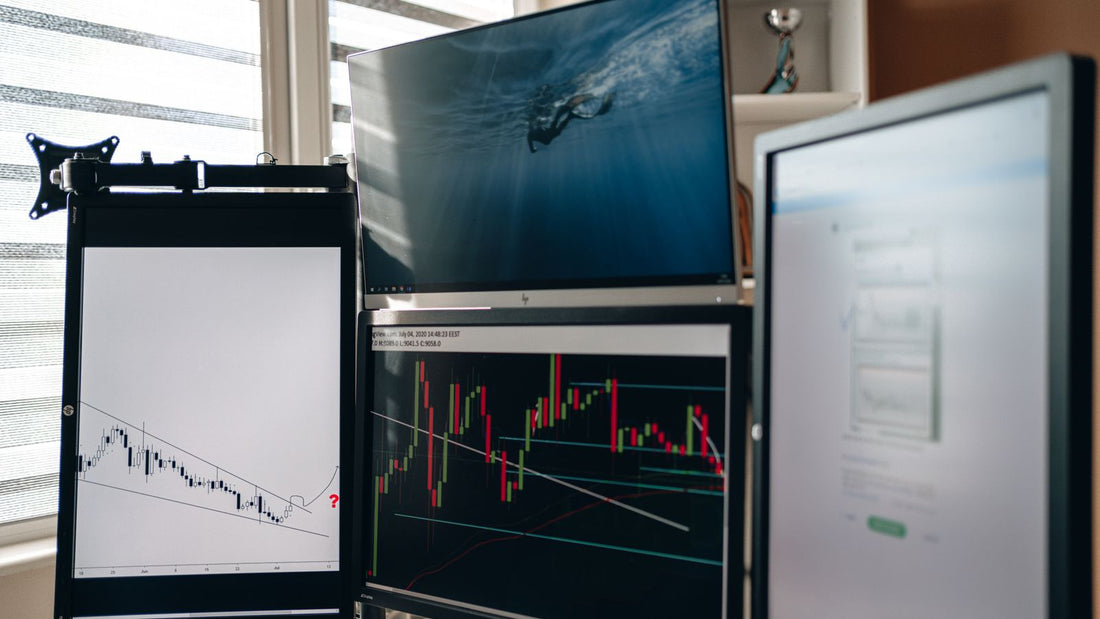 Postazione di trading con più monitor e grafici finanziari