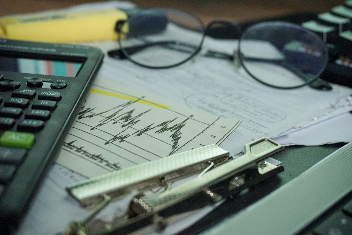 Scrivania di investitore con computer, calcolatrice e documenti finanziari