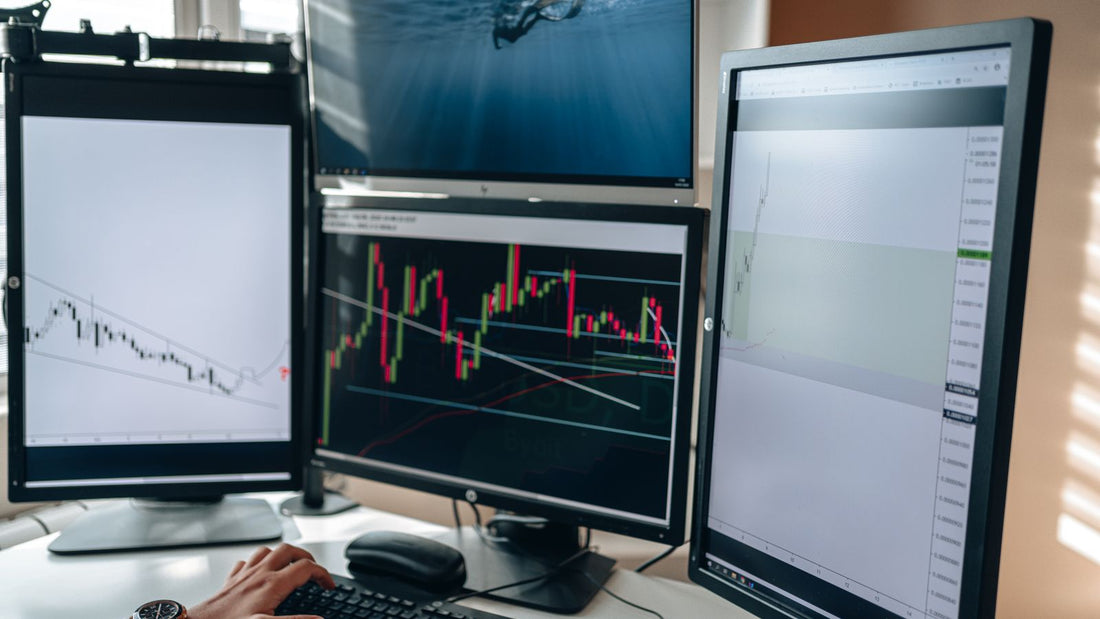 Postazione di trading con diversi monitor e grafici di mercato, immagine illustrativa di una prop firm