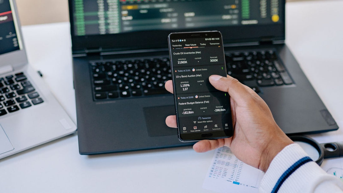 Persona che controlla grafici finanziari da laptop e smartphone