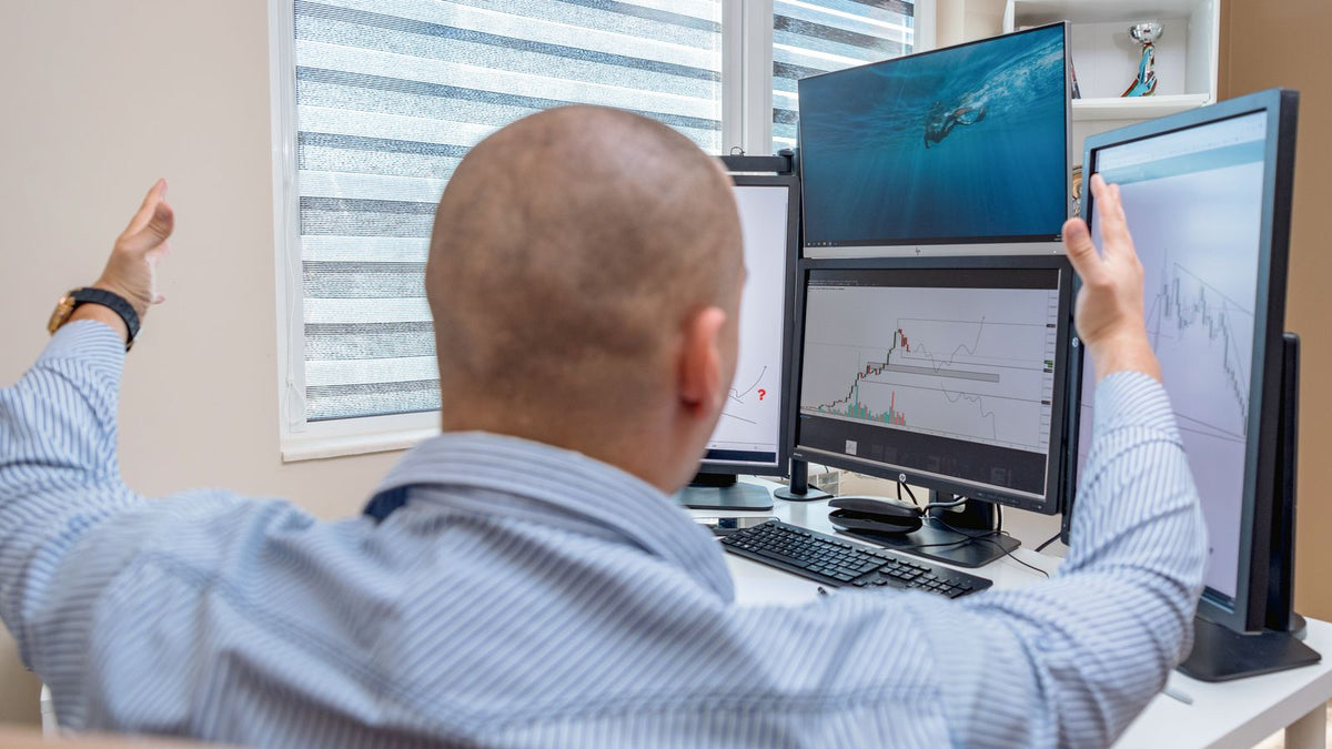 Trader che festeggia un risultato davanti a monitor con grafici finanziari, obiettivi e take profit