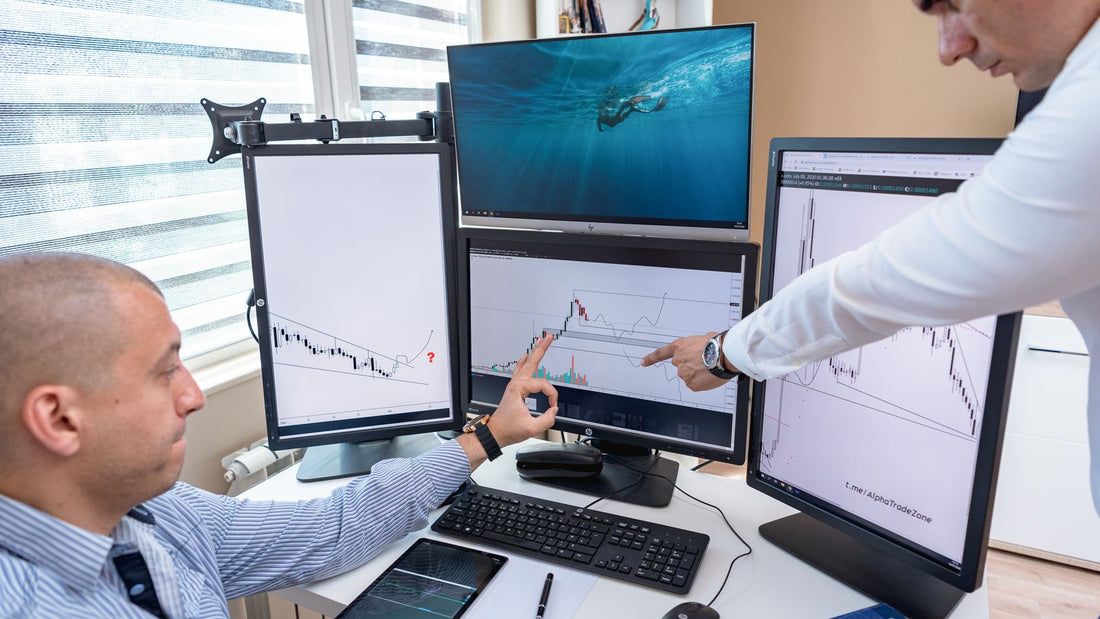 Due professionisti esaminano grafici di mercato su monitor in ufficio, immagine illustrativa