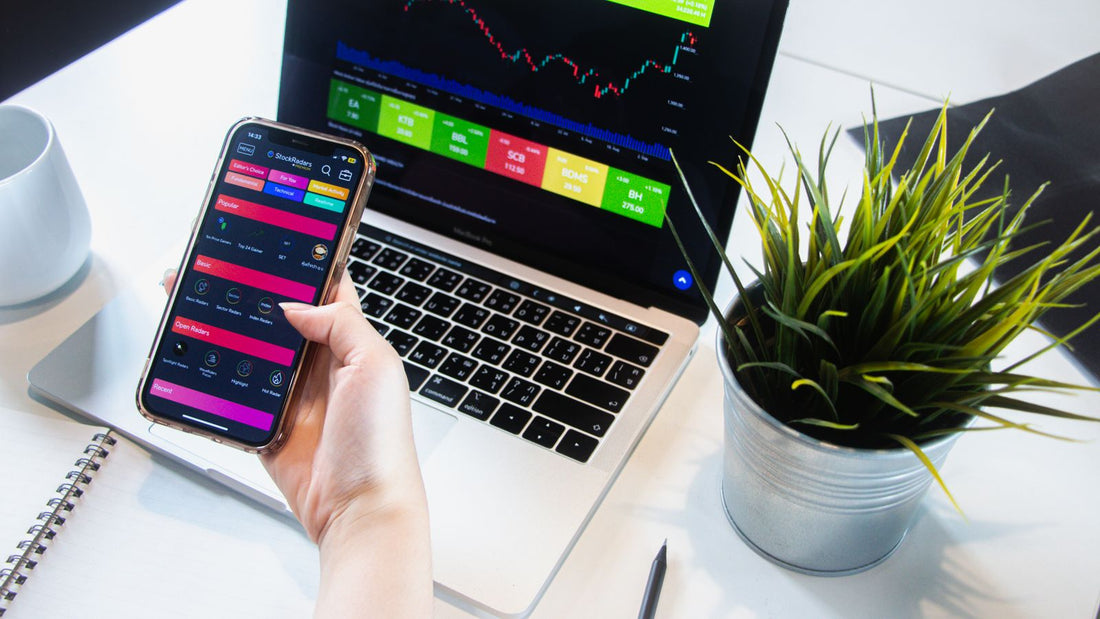 Persona che utilizza smartphone e laptop per controllare quotazioni e grafici dei mercati