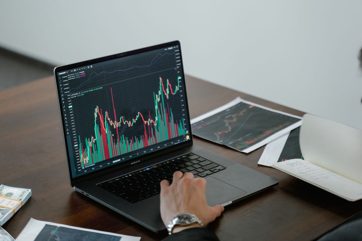 Grafici finanziari aperti su laptop in una postazione di trading